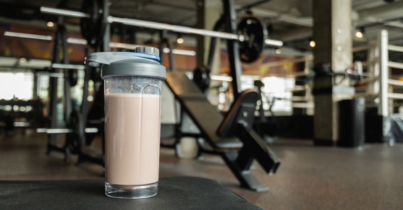 Shaker z odżywką białkową położony na boxie w siłowni