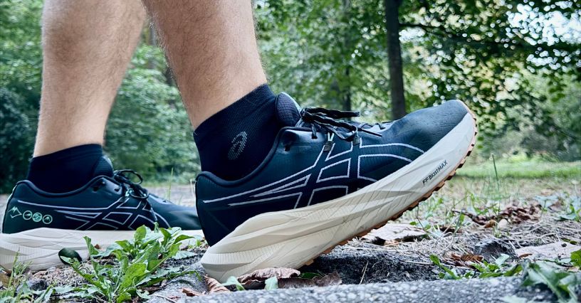 Noga biegacza w butach biegowych ASICS Blazeblast i skarpetach ASICS Performance Run Quarter na trawie